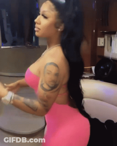 A Woman In A Pink Dress Has A Tattoo On Her Arm Of A Man 'S Face GIF