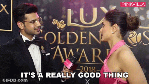 A Woman In A Pink Dress Is Being Interviewed By A Man In A Tuxedo At The Lux Golden Awards 2018 GIF