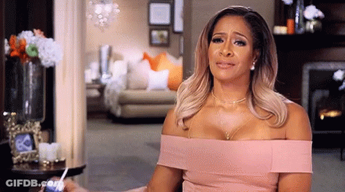 A Woman In A Pink Dress Is Crying In A Living Room . GIF