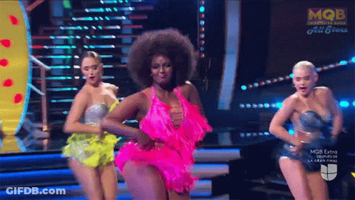 A Woman In A Pink Dress Is Dancing On Stage GIF