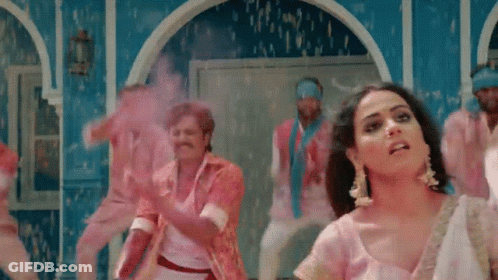 A Woman In A Pink Dress Is Dancing With A Group Of Men GIF