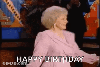 A Woman In A Pink Dress Is Dancing With The Words `` Happy Birthday '' Behind Her . GIF