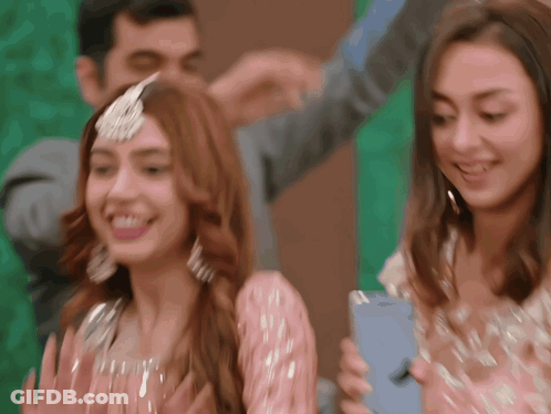 A Woman In A Pink Dress Is Holding A Blue Iphone GIF