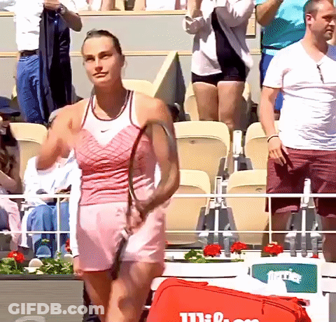 A Woman In A Pink Dress Is Holding A Tennis Racquet GIF