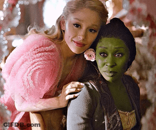 A Woman In A Pink Dress Is Hugging A Woman In A Green Dress GIF