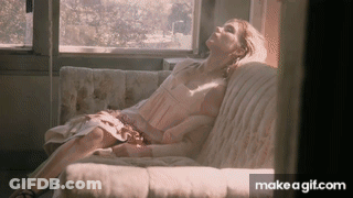 A Woman In A Pink Dress Is Laying On A Couch With Her Eyes Closed GIF