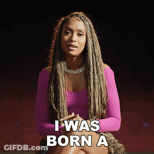 A Woman In A Pink Dress Is Sitting Down And Says I Was Born A GIF