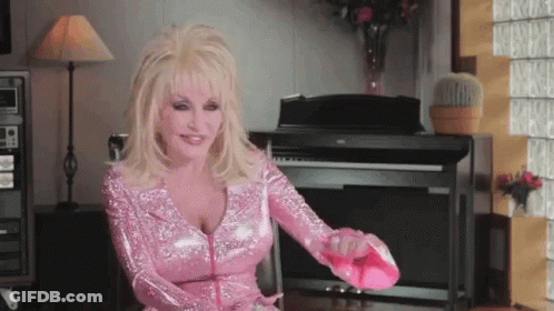 A Woman In A Pink Dress Is Sitting In Front Of A Piano And Holding A Pink Shoe . GIF