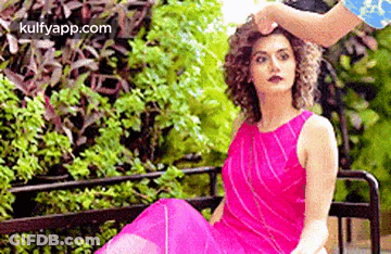 A Woman In A Pink Dress Is Sitting On A Bench While A Man Holds Her Hair . GIF