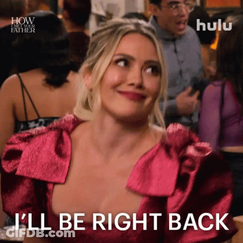 A Woman In A Pink Dress Is Smiling And Says I 'Ll Be Right Back GIF