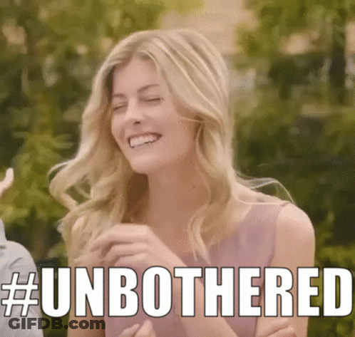 A Woman In A Pink Dress Is Smiling With The Words # Unbothered Written Above Her . GIF