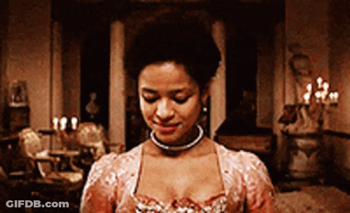 A Woman In A Pink Dress Is Standing In A Room With Candles On The Walls GIF