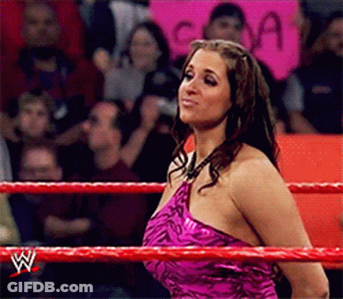 A Woman In A Pink Dress Is Standing In A Wrestling Ring With A W Logo On The Ropes GIF