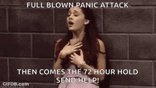 A Woman In A Pink Dress Is Standing In Front Of A Brick Wall With Her Hand On Her Chest . GIF