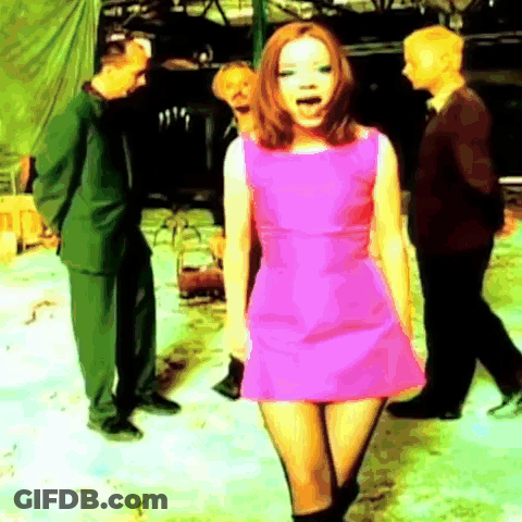 A Woman In A Pink Dress Is Standing In Front Of A Group Of People GIF