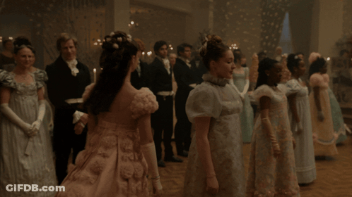 A Woman In A Pink Dress Is Standing In Front Of A Man In A Black Suit GIF