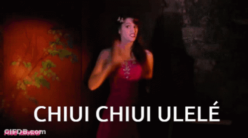A Woman In A Pink Dress Is Standing In Front Of A Sign That Says Chiui Chiui Ulele GIF