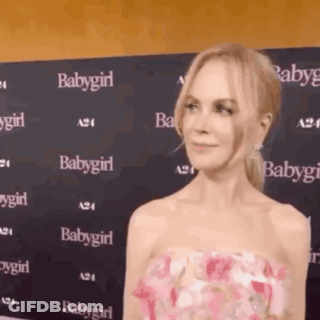 A Woman In A Pink Dress Is Standing In Front Of A Wall That Says Babygirl On It . GIF