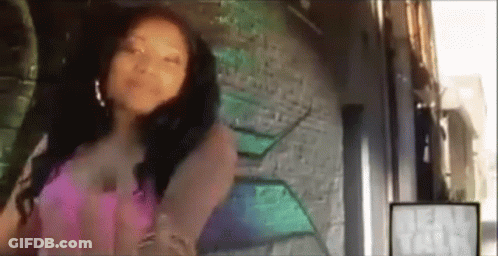 A Woman In A Pink Dress Is Standing In Front Of A Wall With Graffiti On It . GIF