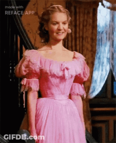 A Woman In A Pink Dress Is Standing In Front Of Stairs Made With Reface App GIF