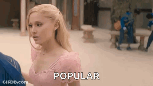 A Woman In A Pink Dress Is Standing Next To A Man And Talking To Him . GIF