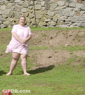 A Woman In A Pink Dress Is Standing On A Grassy Hill . GIF