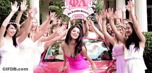 A Woman In A Pink Dress Is Surrounded By Other Women In Front Of A Car That Says Phi Lambda Sorority GIF