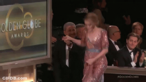 A Woman In A Pink Dress Is Walking On A Stage At The Golden Globe Awards GIF