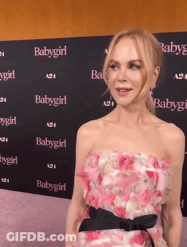 A Woman In A Pink Dress Stands In Front Of A Wall With Babygirl Written On It GIF