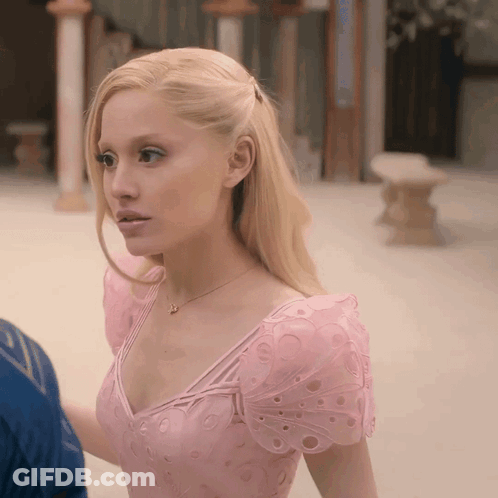 A Woman In A Pink Dress With Butterfly Sleeves Looks To The Side GIF