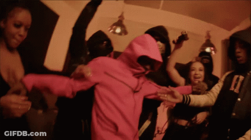 A Woman In A Pink Hoodie Is Surrounded By A Crowd Of People GIF