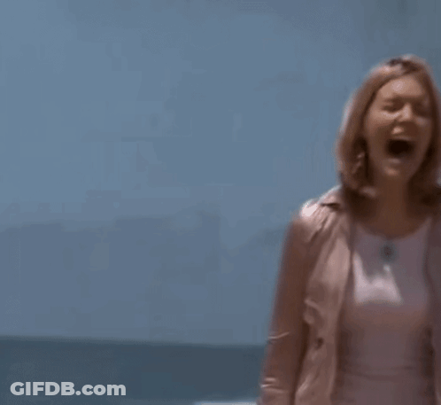 A Woman In A Pink Jacket And A White Skirt Is Standing On A Beach . GIF