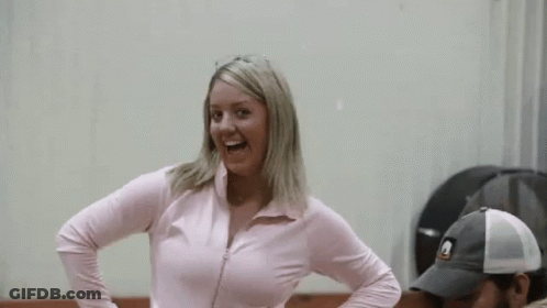 A Woman In A Pink Jacket Is Dancing With A Man In A Hat GIF