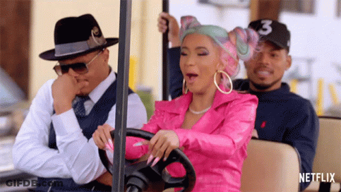 A Woman In A Pink Jacket Is Driving A Golf Cart With Two Men In Suits . GIF