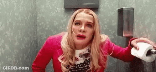 A Woman In A Pink Jacket Is Holding A Roll Of Toilet Paper In A Bathroom . GIF