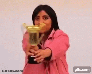 A Woman In A Pink Jacket Is Holding A Trophy . GIF