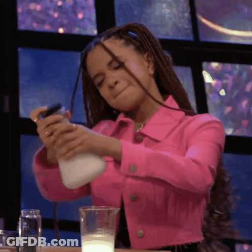 A Woman In A Pink Jacket Is Pouring Milk Into A Cup GIF