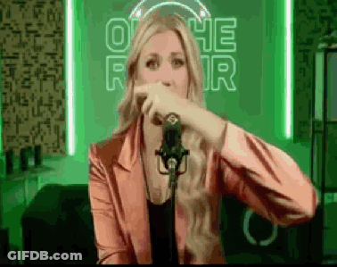 A Woman In A Pink Jacket Is Singing Into A Microphone In Front Of A Neon Sign That Says Othe For GIF