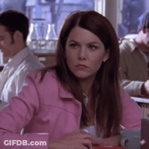 A Woman In A Pink Jacket Is Sitting At A Table With Other People GIF