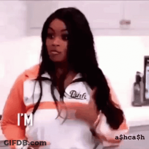 A Woman In A Pink Jacket Is Standing In A Kitchen Holding A Cup Of Coffee . GIF