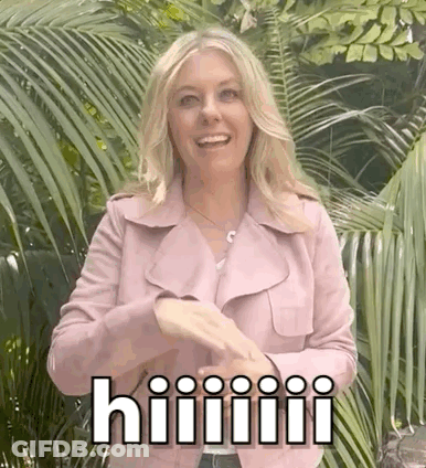 A Woman In A Pink Jacket Is Standing In Front Of Palm Trees And Making A Funny Face . GIF