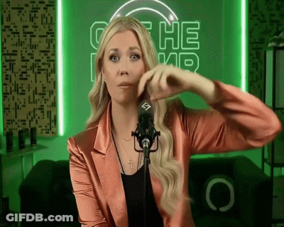 A Woman In A Pink Jacket Stands In Front Of A Microphone In Front Of A Green Sign That Says ' The ' GIF