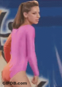 A Woman In A Pink Leotard Stands In Front Of A Blue Background GIF