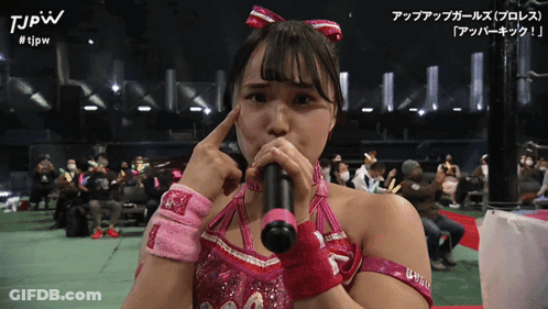 A Woman In A Pink Outfit Is Holding A Microphone And The Words Tjpw Are On The Bottom Right GIF