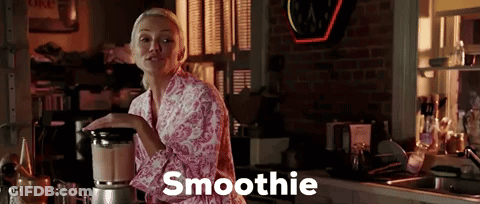 A Woman In A Pink Robe Is Making A Smoothie GIF