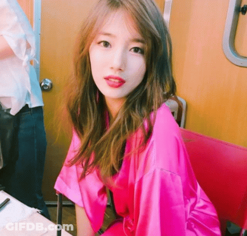 A Woman In A Pink Robe Sits In A Chair GIF