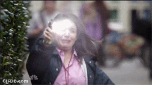 A Woman In A Pink Shirt And A Blue Jacket Is Holding A Flashlight GIF