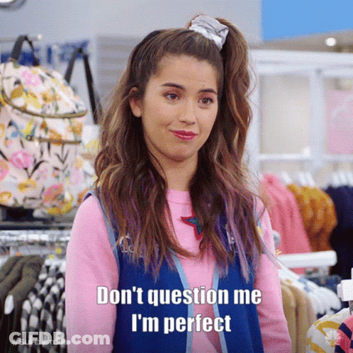 A Woman In A Pink Shirt And Blue Vest Says " Don 'T Question Me I 'M Perfect " In A Store . GIF
