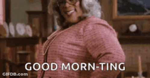 A Woman In A Pink Shirt And Glasses Is Standing In A Living Room And Saying `` Good Morning - Ting '' . GIF