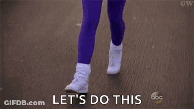 A Woman In A Pink Shirt And Purple Pants Is Running Down A Street And Says `` Let 'S Do This '' . GIF